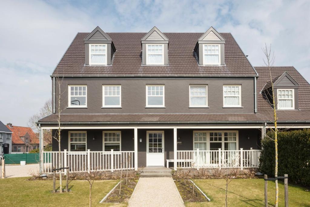 a large house with a brown roof and white doors at Morris Coffee & Crafts in Ruddervoorde