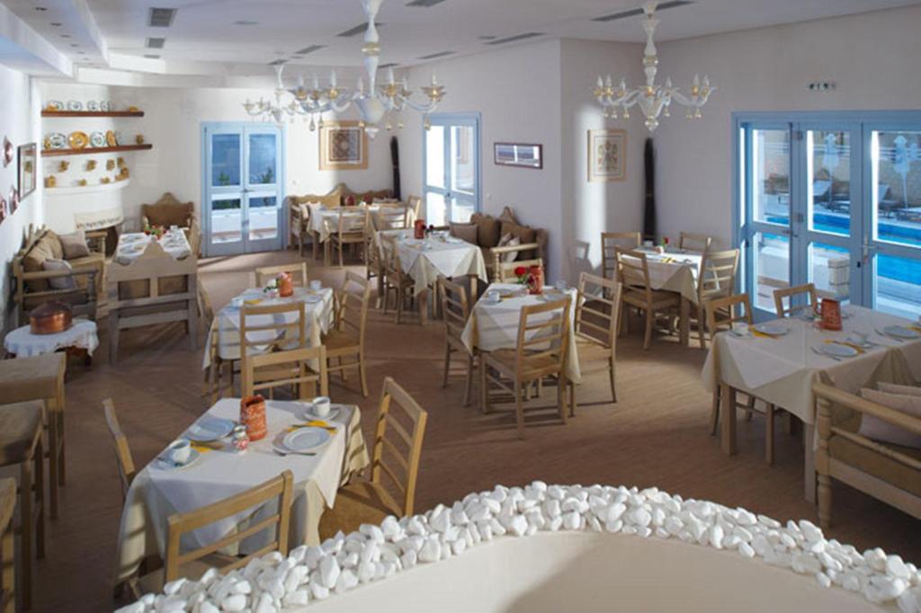 a restaurant with white tables and chairs and chandeliers at Perigiali in Skiros