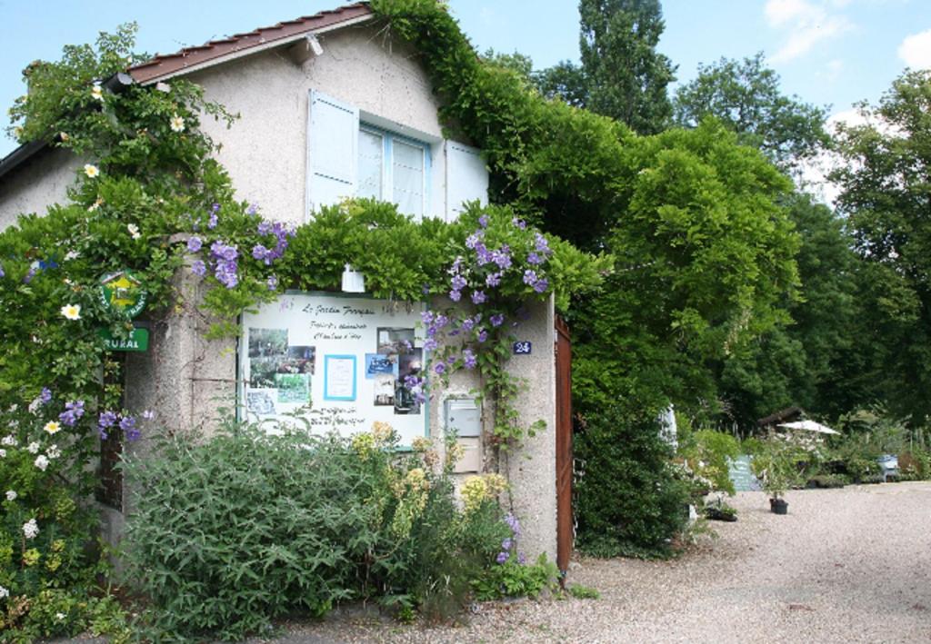 une maison avec des fleurs sur son côté dans l'établissement Gîtes du Jardin Francais, à Ermenonville