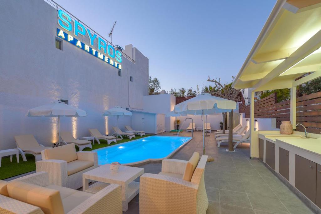 a hotel with a swimming pool with chairs and umbrellas at Spyros Apartments with Pool in Kalamaki