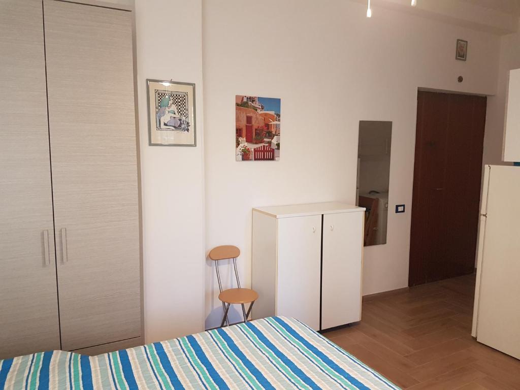 een slaapkamer met een bed, een koelkast en een stoel bij Casa Vittoria in Gaeta