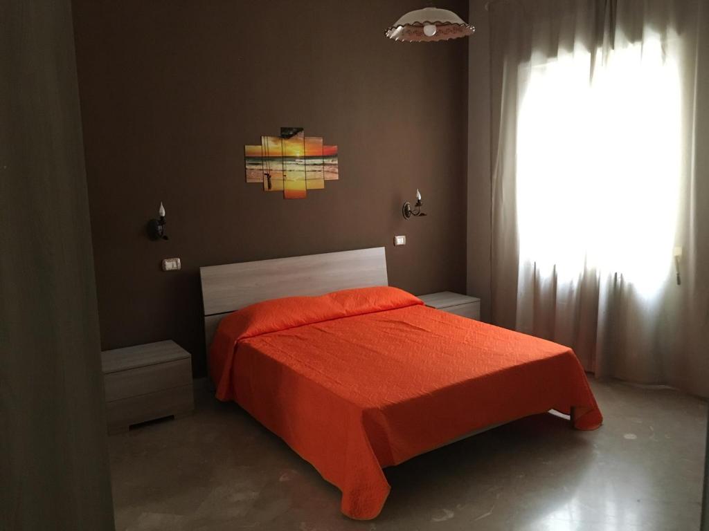 sypialnia z czerwonym łóżkiem i oknem w obiekcie ZeroSalento Casa Vacanze w mieście Monteroni di Lecce