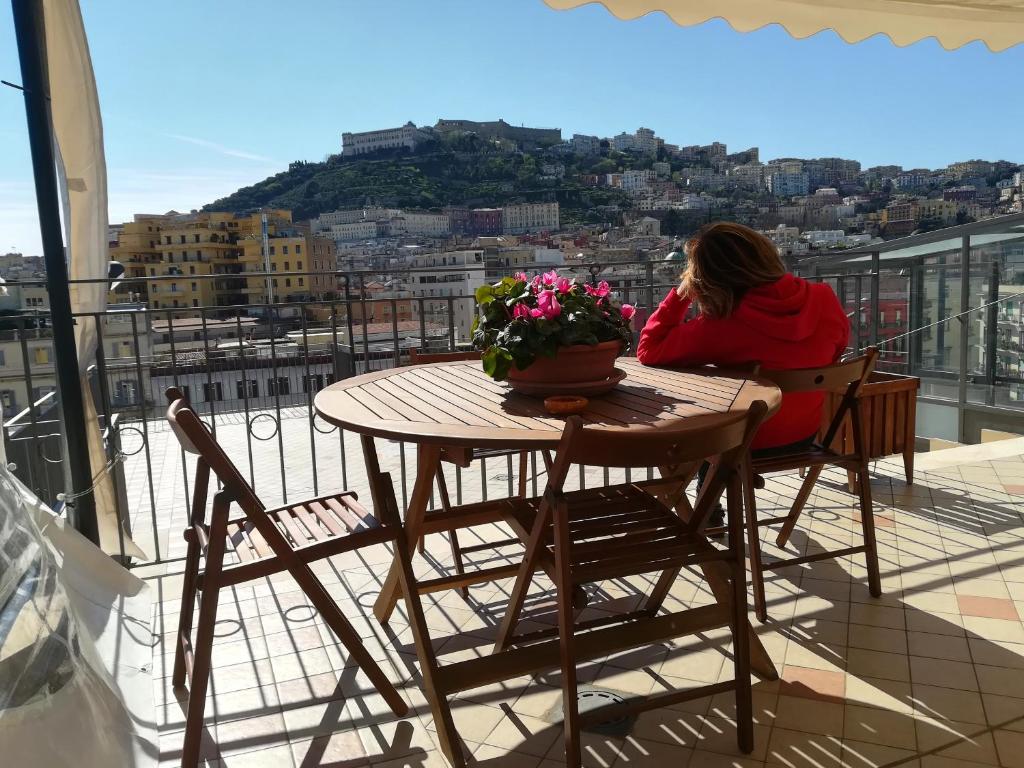una donna seduta a un tavolo sul balcone di Annunziata Bed and Breakfast a Napoli