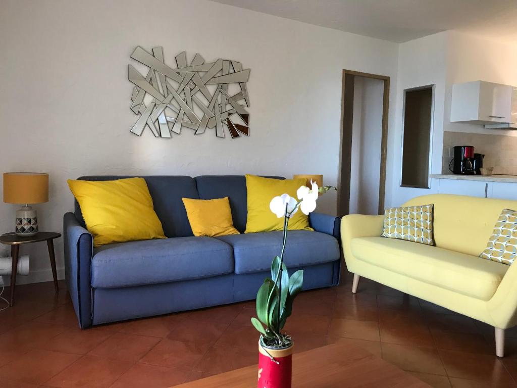 a living room with a blue couch and yellow pillows at Residence port la galere in Théoule-sur-Mer