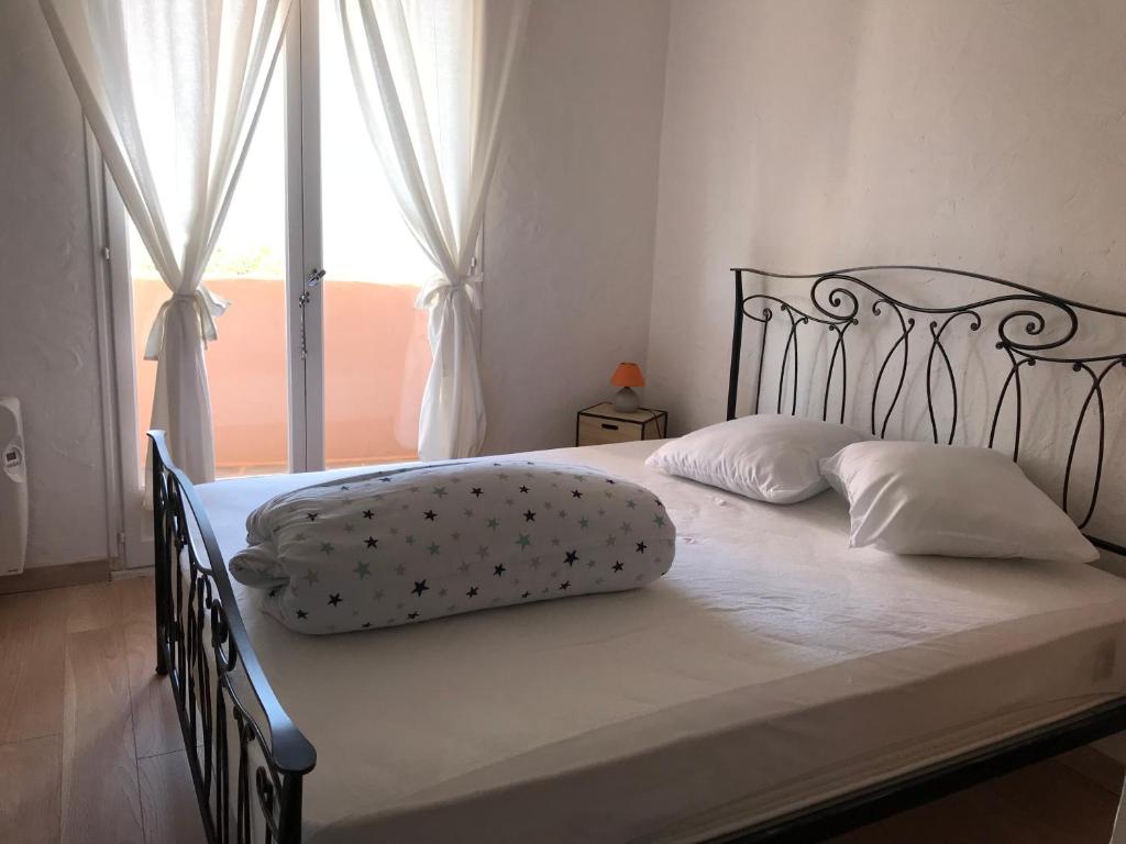 a bed with white sheets and pillows and a window at Residence port la galere in Théoule-sur-Mer