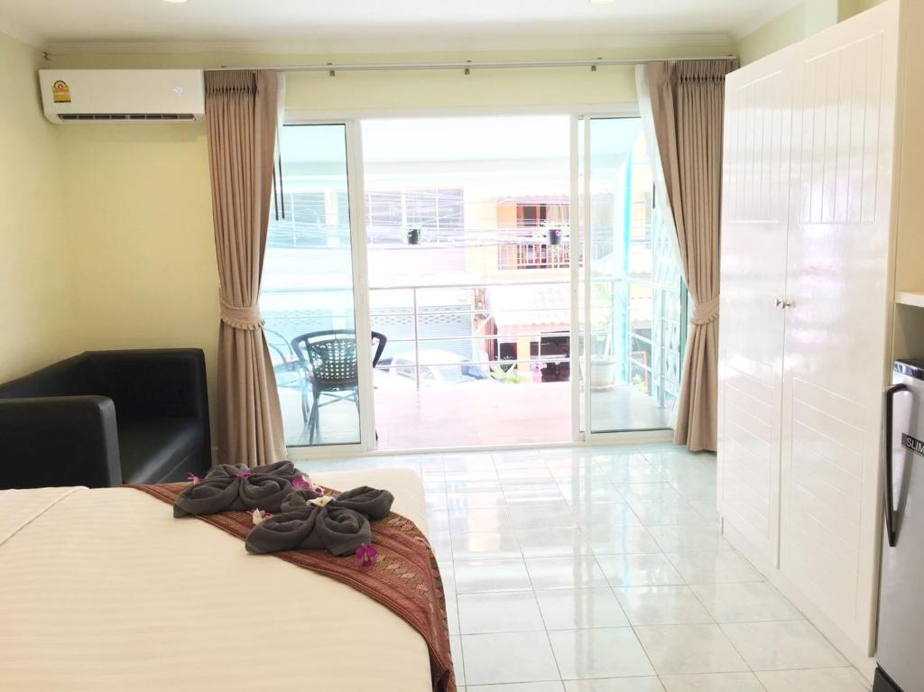 a bedroom with a bed and a view of a balcony at Thai Orchid Guest House in Jomtien Beach