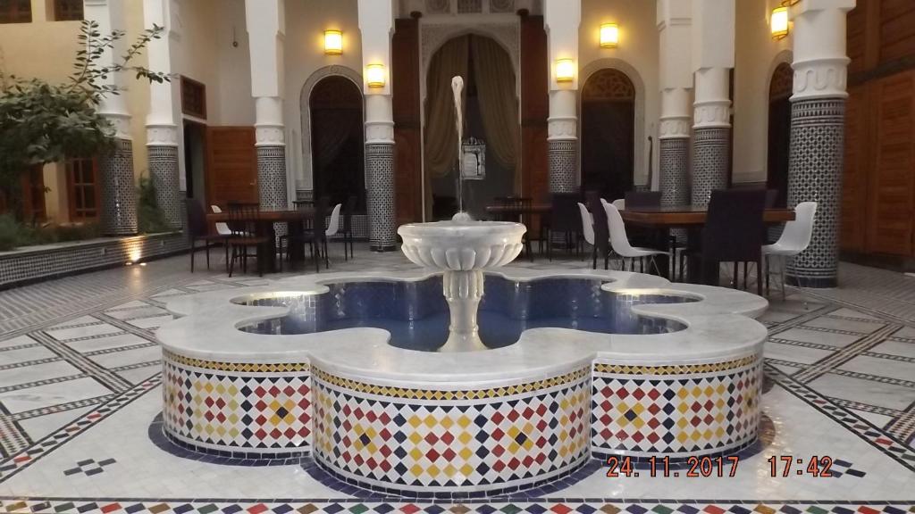 een fontein in het midden van een gebouw met tafels en stoelen bij Riad jasmins & Spa in Fès