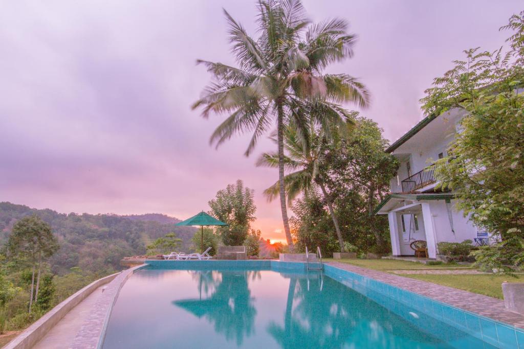 a swimming pool in front of a house with a palm tree at Old Frankland Kandy Luxury Boutique Hotel in Kandy