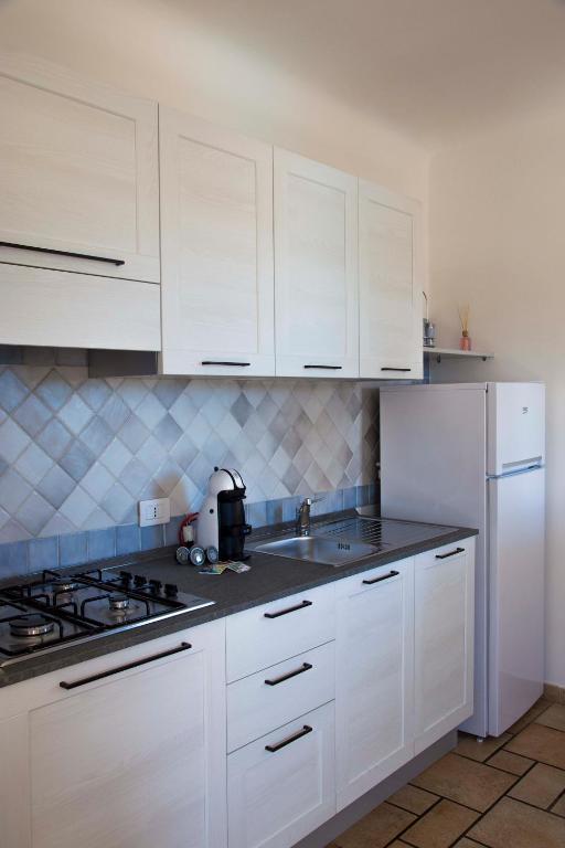 a white kitchen with white cabinets and a sink at Bados Mare in Olbia