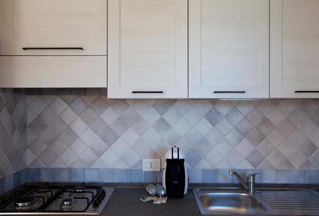 a kitchen with white cabinets and a stove and a sink at Bados Mare in Olbia