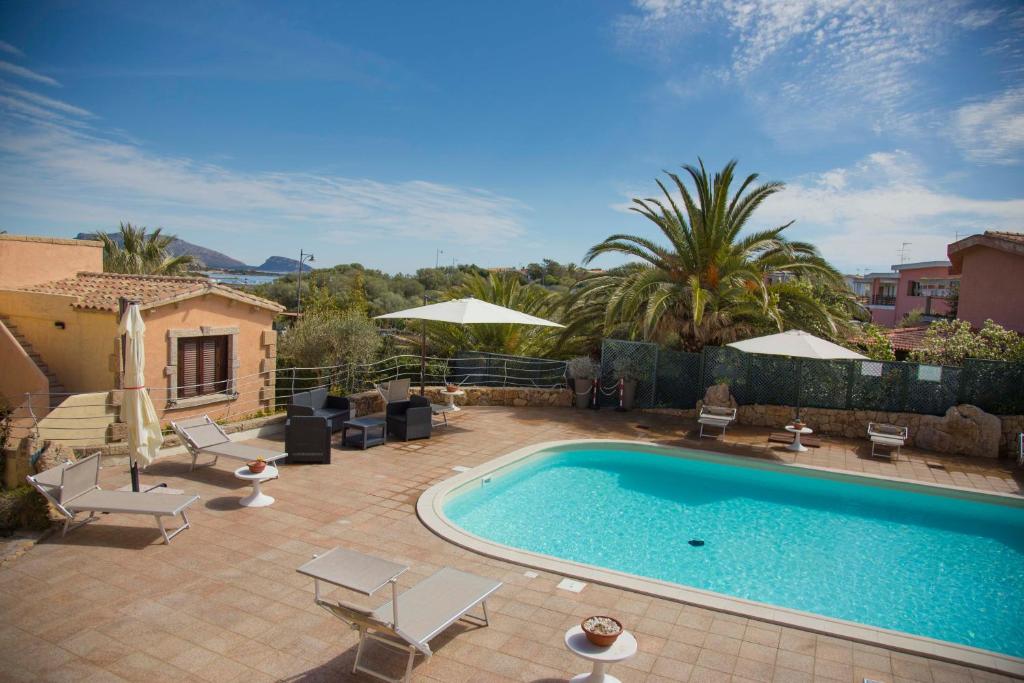 a swimming pool in a yard with chairs and umbrellas at Bados Mare in Olbia