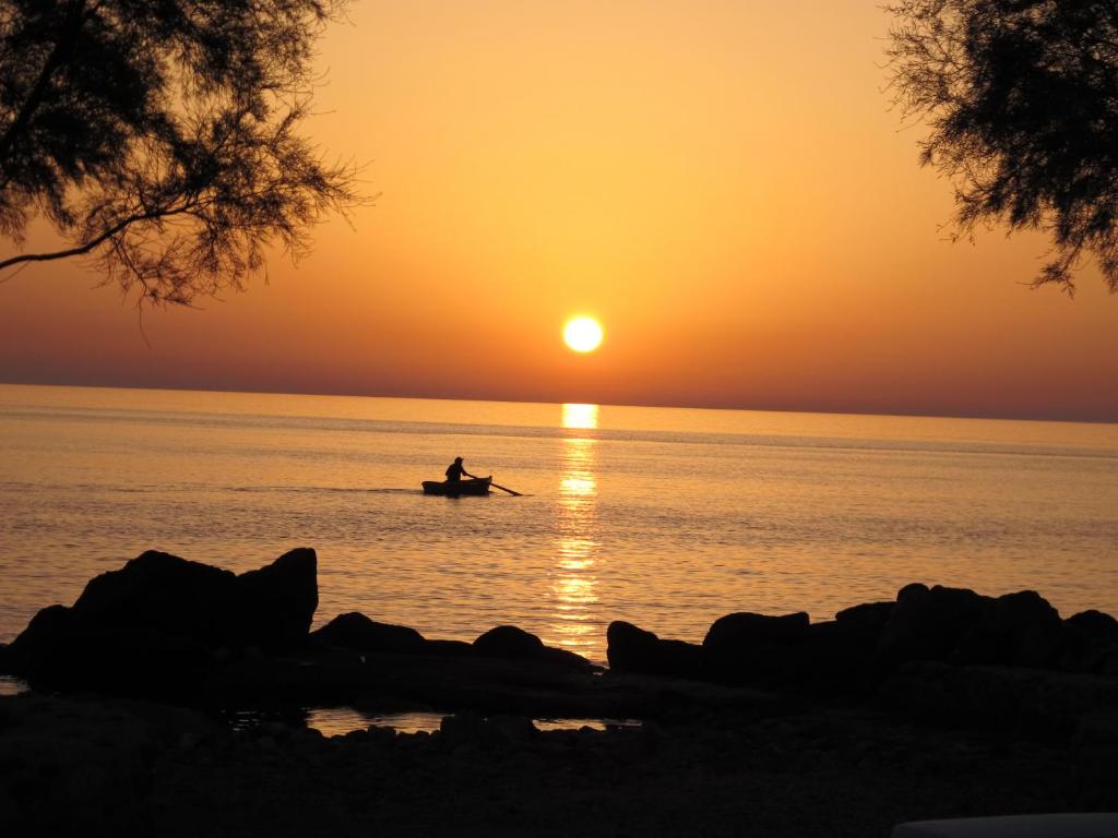 a person in a boat in the water at sunset at Oklacà Patmos Beach Rooms in Patmos