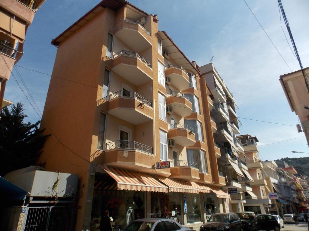 een hoog geel gebouw met balkons in een straat bij Hotel Veli in Sarandë