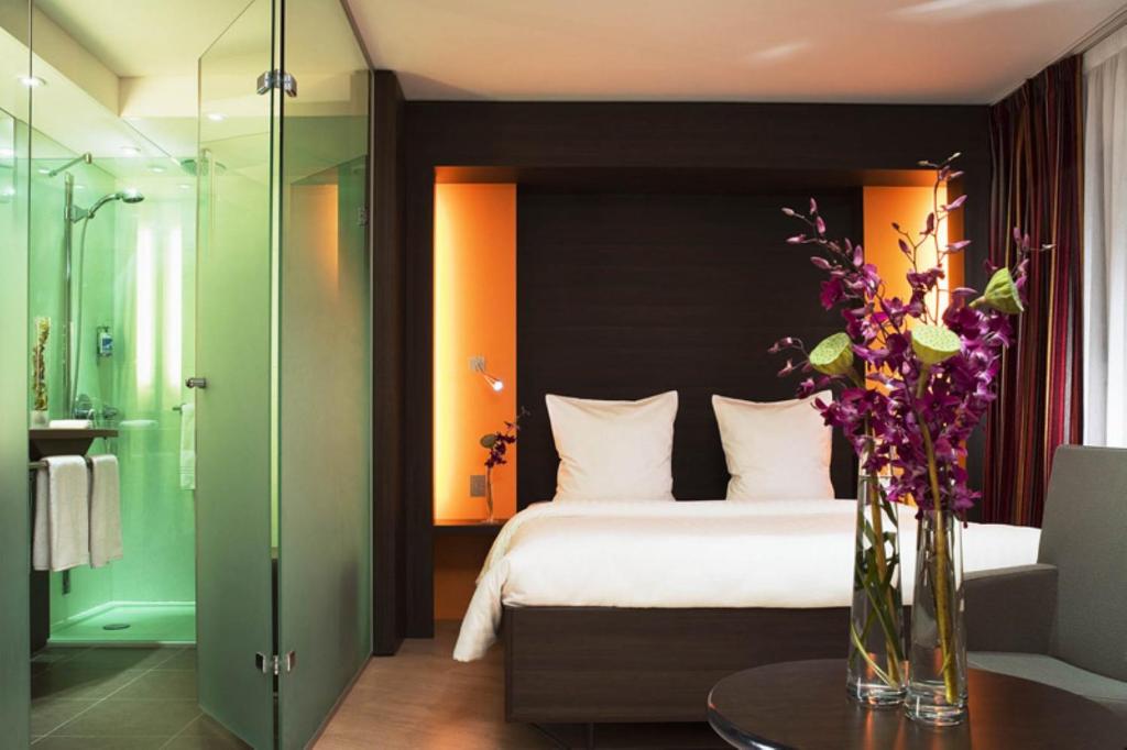 a bedroom with a bed and a vase of flowers on a table at Hôtel Oceania Brest in Brest