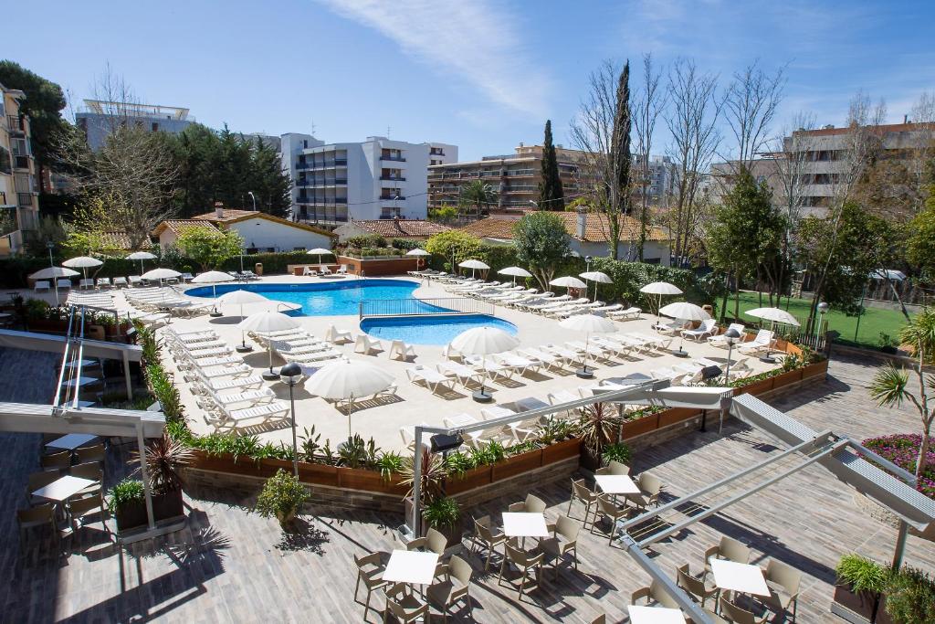 an outdoor pool with white chairs and umbrellas at Aparthotel Cye Holiday Centre in Salou