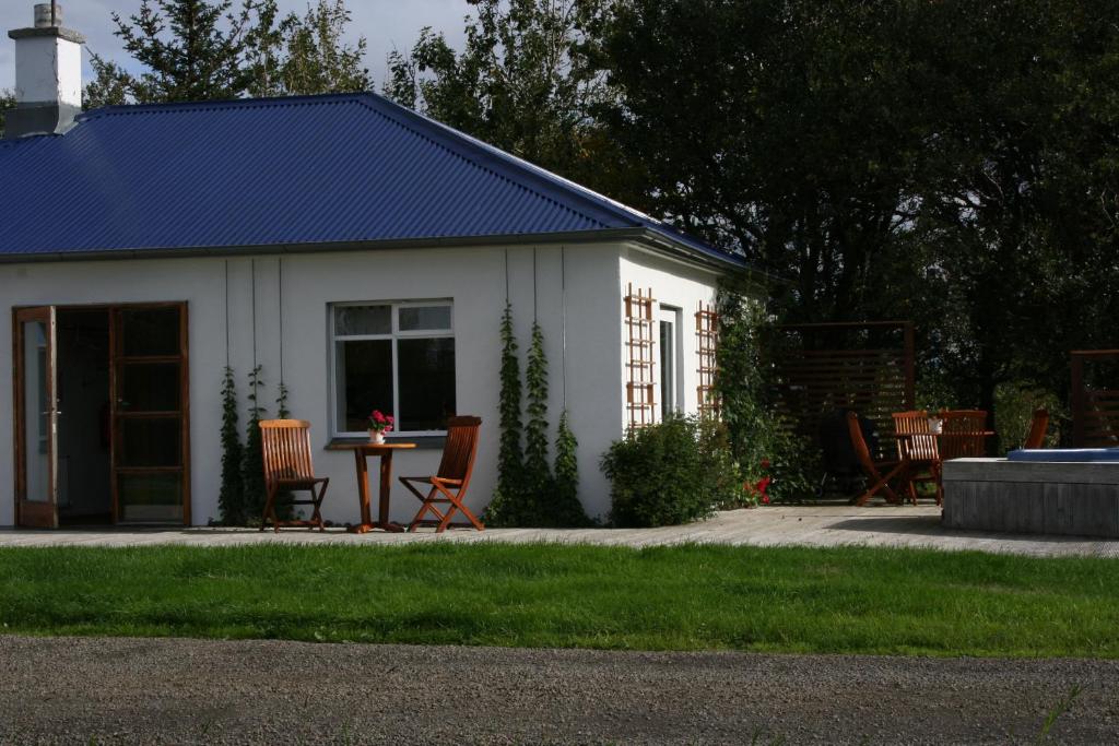a white building with chairs and a table in a yard at Jadar Farm in Bær