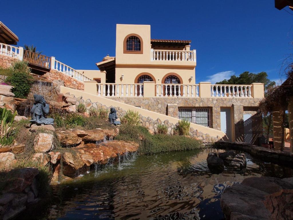 ein Haus mit einem Teich vor einem Gebäude in der Unterkunft Cas Llop Ibiza Luxury Views in Cala Tarida