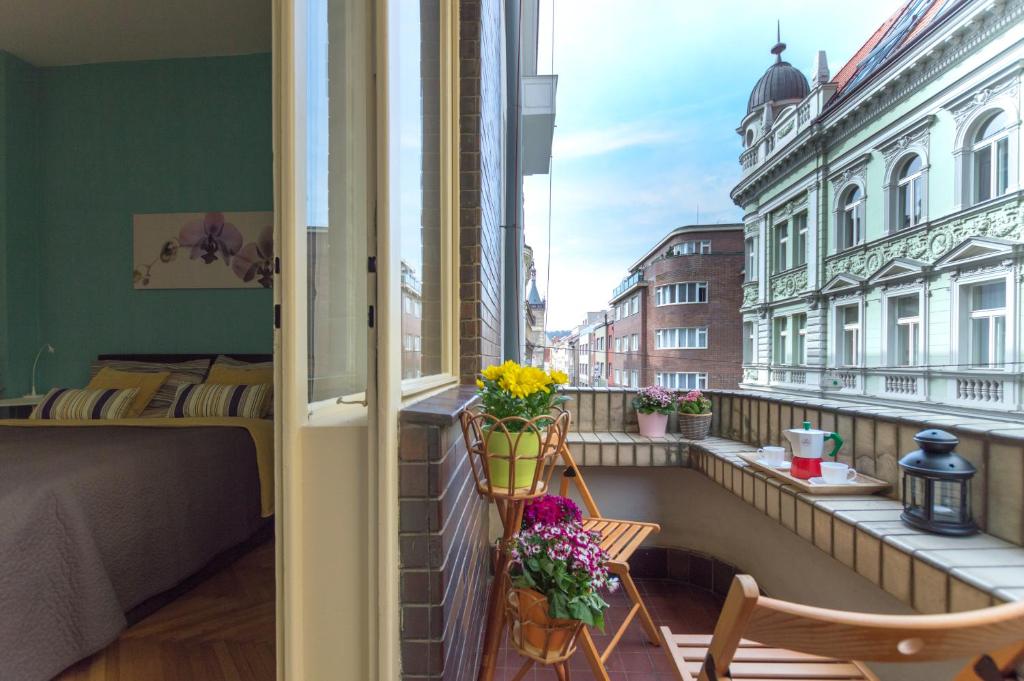 プラハにあるCentral Apartments With Terraceの花の咲くバルコニー、ベッド、窓が備わります。