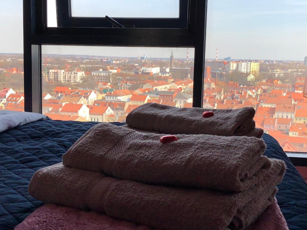 uma pilha de toalhas sentadas numa cama em frente a uma janela em Sky-scraper em Klaipėda