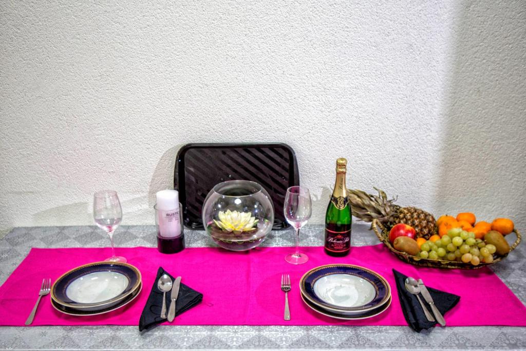 a table with a pink table cloth with wine glasses and fruit at Kingdom Rooms Visoko in Visoko