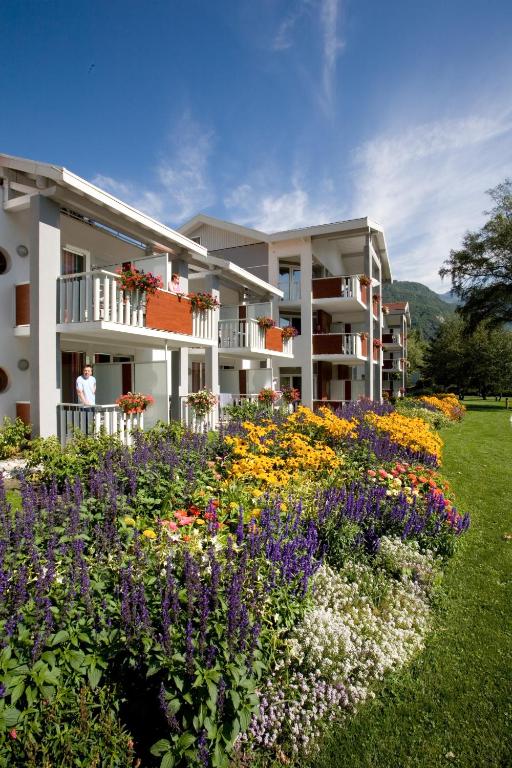 un bâtiment avec un jardin fleuri devant lui dans l'établissement Residence RADIANA, à La Léchère