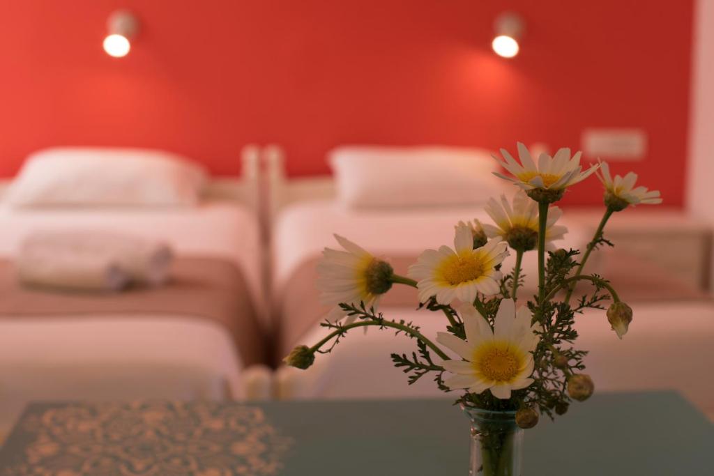 a vase with flowers on a table in a room with beds at Niki Rooms in Palaiochóra