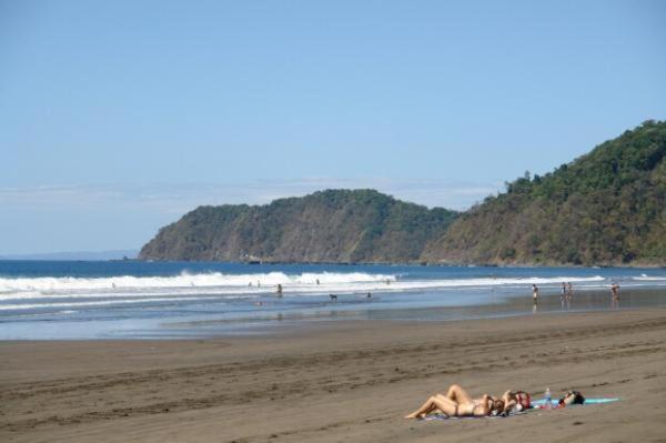 a group of people laying on the beach at Alquiler de Villas - Condominio en Jacó in Jacó