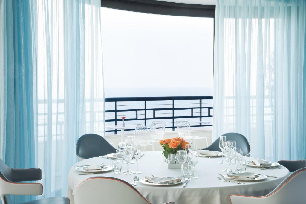 a dining room with a table and chairs and a large window at JR Hotels Bari Grande Albergo delle Nazioni in Bari