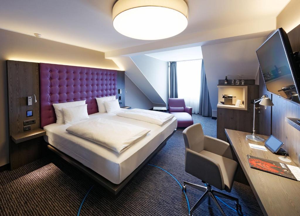 a hotel room with a large bed and a desk at Hotel Stadt München in Düsseldorf
