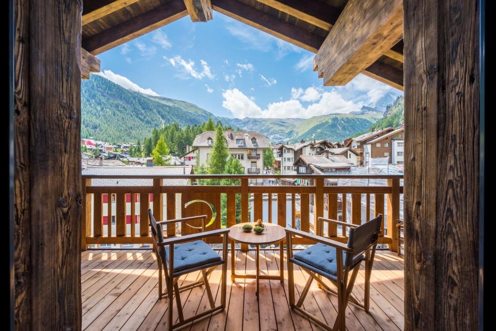 a balcony with a table and chairs and a view of mountains at Christiania Residence in Zermatt