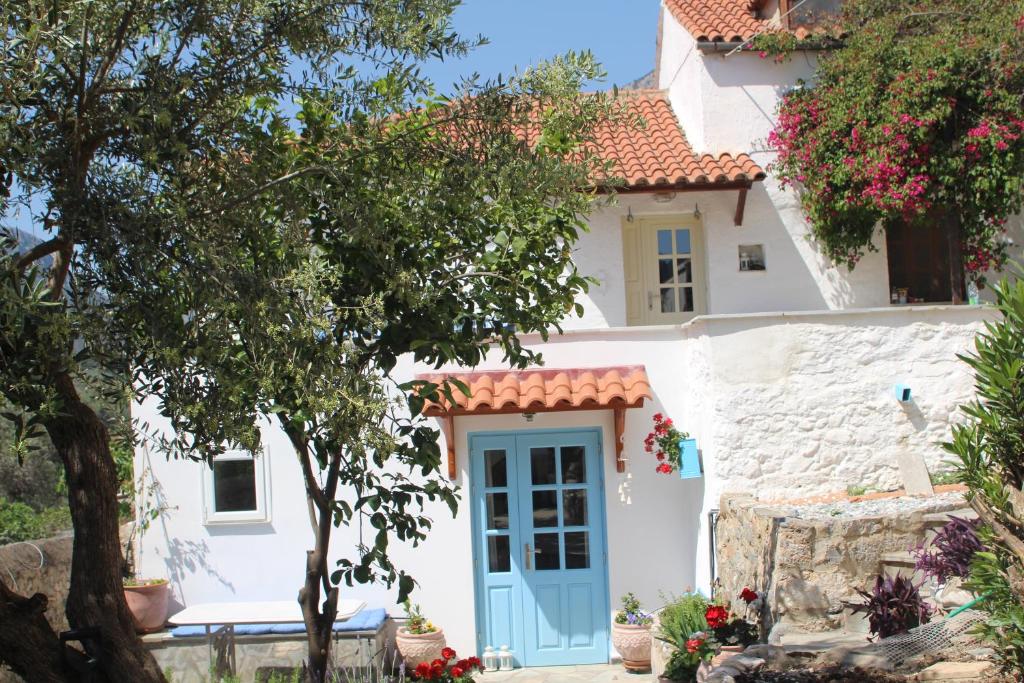 una casa blanca con una puerta azul en The Studio, Leonidio, en Leonidio