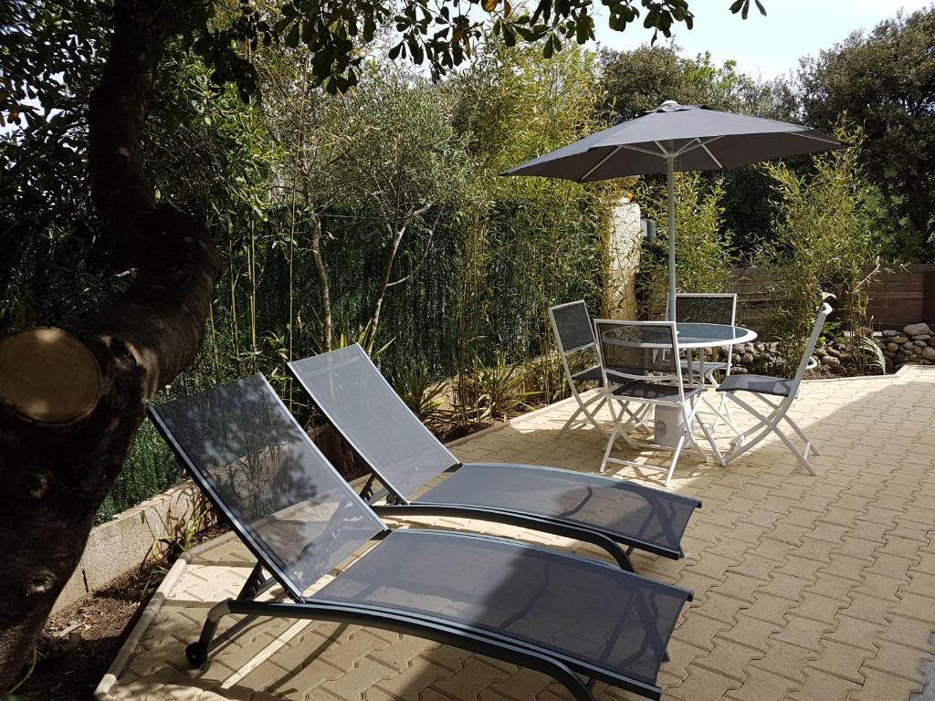 a couple of chairs and an umbrella and a table at Un Charme Absolu in Bastelicaccia