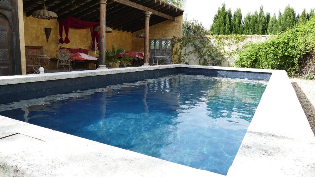 una piscina con acqua blu di fronte a una casa di Mas du Puits d'Amour a Orange