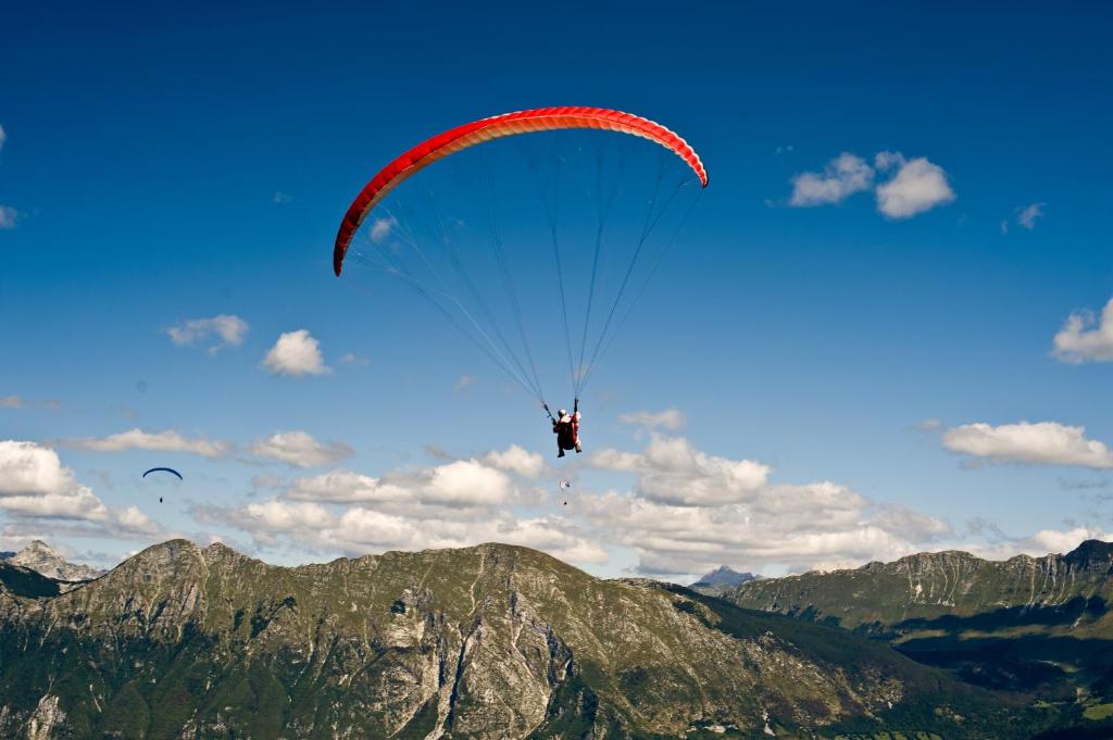 una persona che cavalca un paracadute nel cielo sulle montagne di Hostel X Point a Kobarid