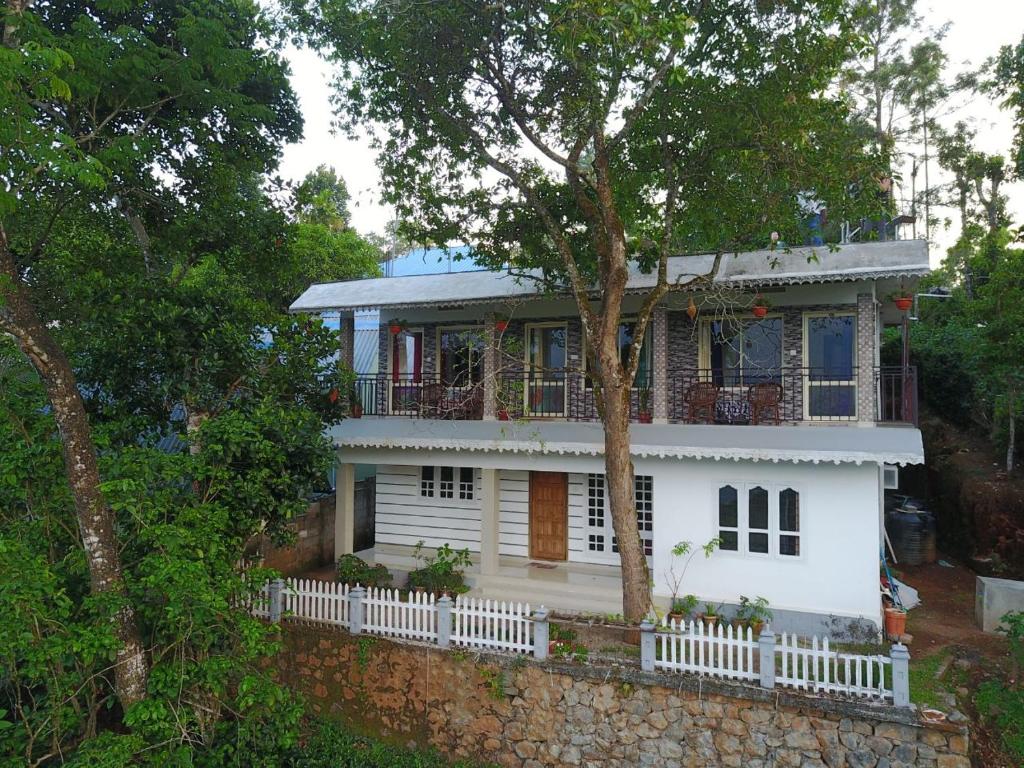 ein weißes Haus mit einem Baum davor in der Unterkunft Green Tea View in Munnar