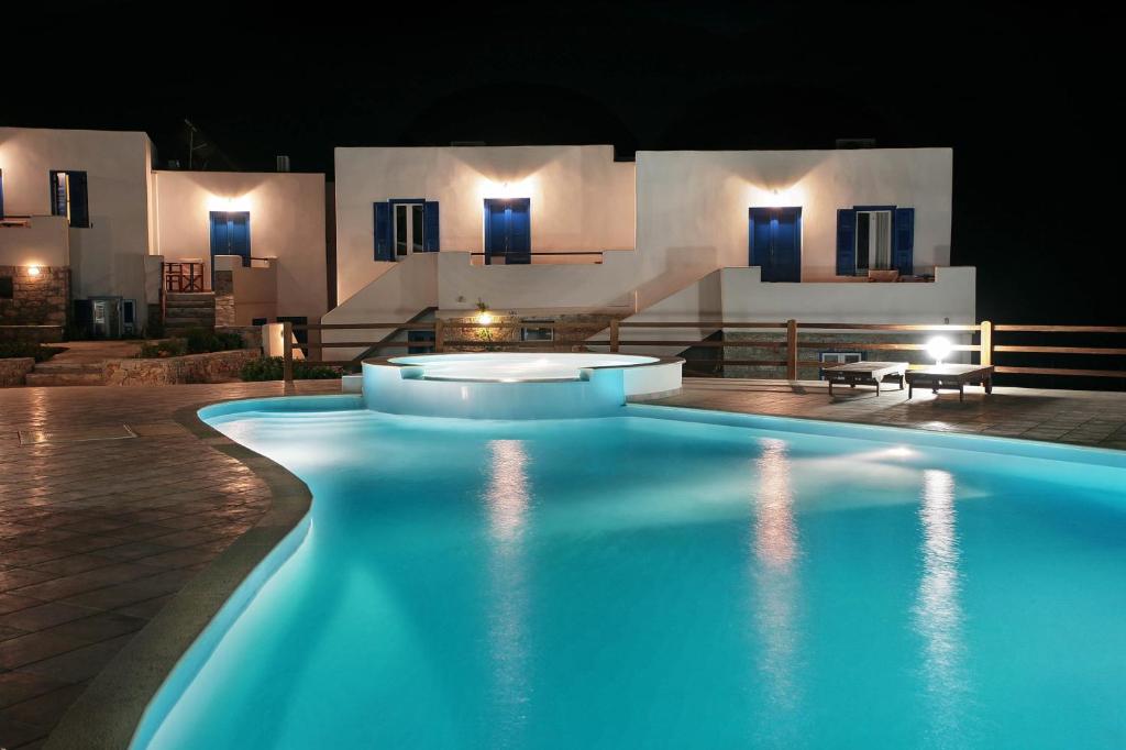 a swimming pool in front of a building at night at Amorgion Village in Katapola