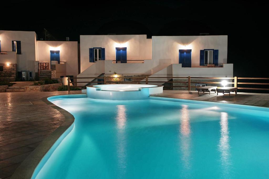 a swimming pool in front of a building at night at Amorgion Hotel in Katapola