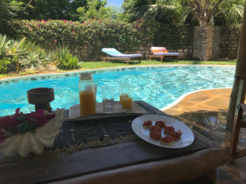 a table with a plate of food next to a swimming pool at Bianca and Pietro House in Watamu