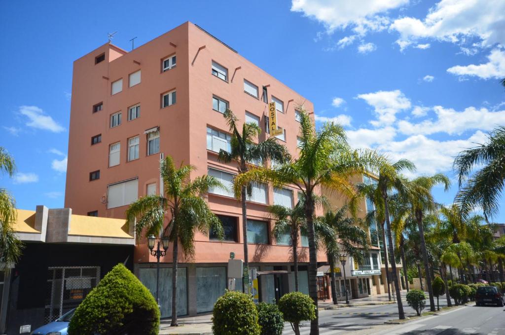 a tall pink building with palm trees in front of it at Hostal La Palmera in Torremolinos