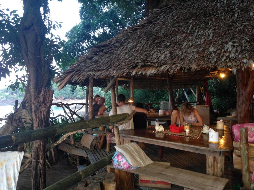 un grupo de personas sentadas en una mesa en una cabaña en Nice View Bungalow en Koh Chang