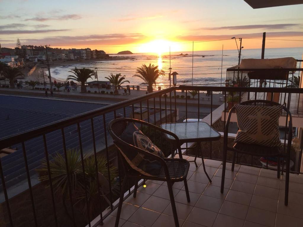 balcón con mesa, sillas y vistas al océano en Departamento Playa Las Cadenas, en Algarrobo
