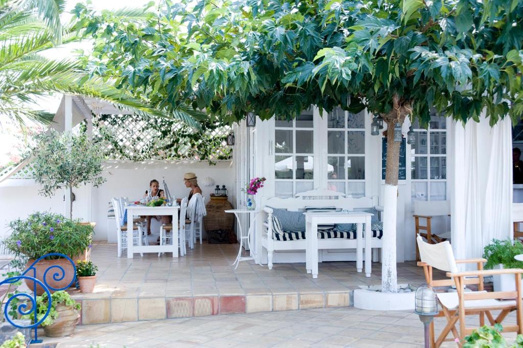 un patio con mesas blancas, sillas y árboles en Villa Ippocampi - Adults Only en Hersonissos