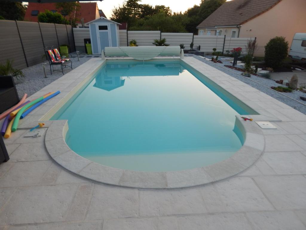 a swimming pool with blue water in a backyard at Audionnière in Saint-Gervais en-Belin