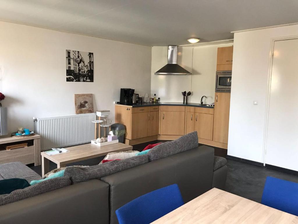 a living room with a couch and a kitchen at Vakantiehuis B&B de Bosrand Groesbeek in Groesbeek