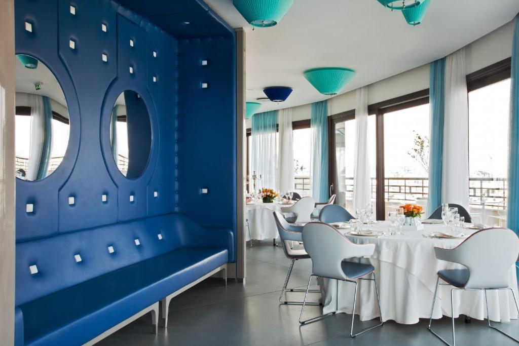 a restaurant with blue walls and white tables and chairs at JR Hotels Bari Grande Albergo delle Nazioni in Bari