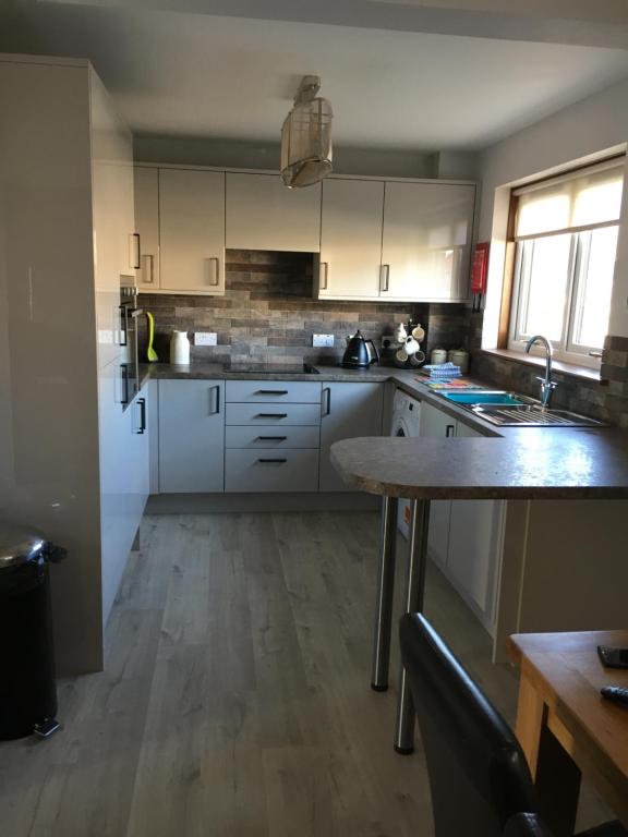 a kitchen with white cabinets and a wooden floor at Christiesholidayhomes in Aviemore