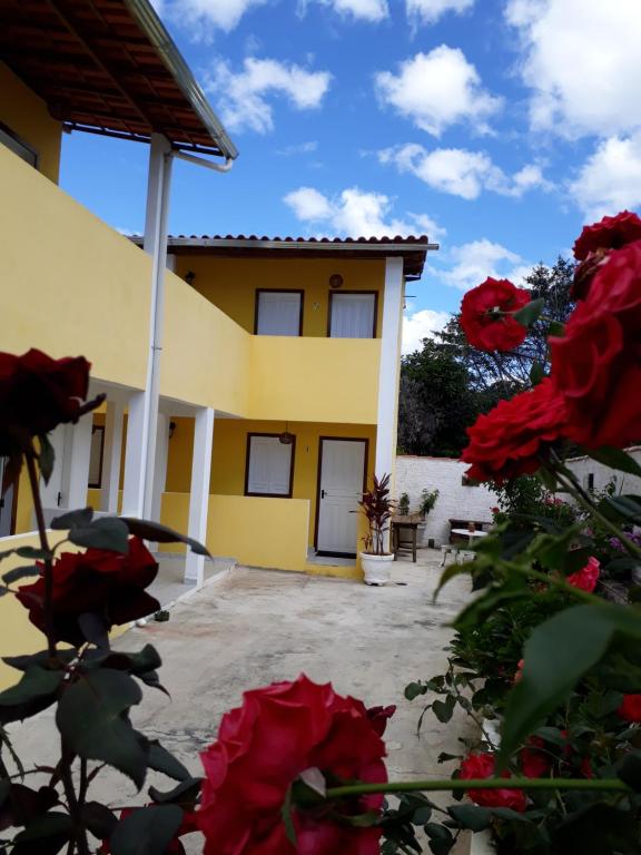 Uma casa com rosas vermelhas à frente. em O Pouso Condomínio em Mucugê