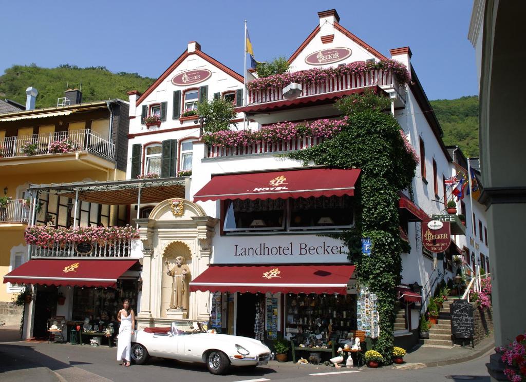 ein weißes Auto, das vor einem Gebäude parkt in der Unterkunft Landhotel Becker in Kamp-Bornhofen