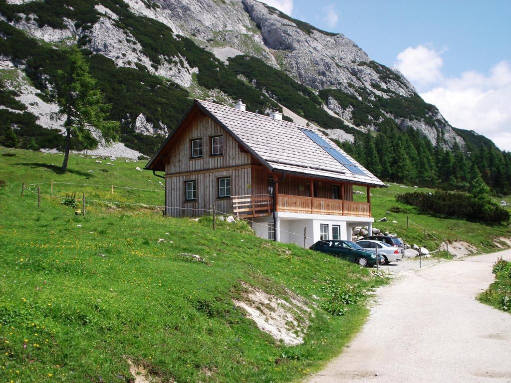 ein Haus auf einem Hügel neben einem Berg in der Unterkunft Gindlhütte in Tauplitzalm