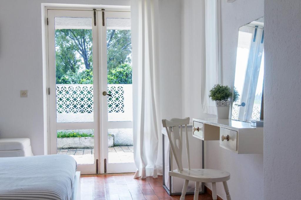 a bedroom with a bed and a chair next to a window at Beach House at Praia da Luz in Luz